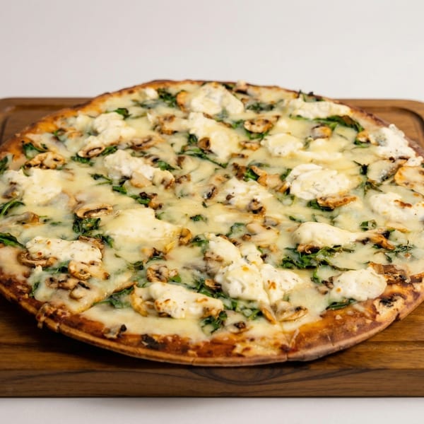 A whole white pizza with mushrooms, spinach, and dollops of ricotta cheese on a wooden board.
